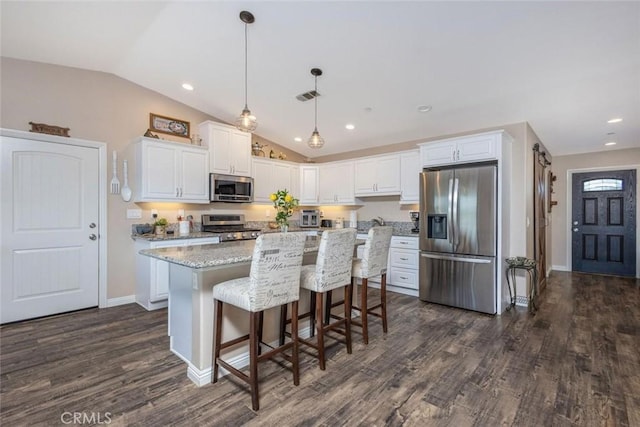 kitchen with visible vents, dark wood finished floors, a kitchen island, appliances with stainless steel finishes, and white cabinetry