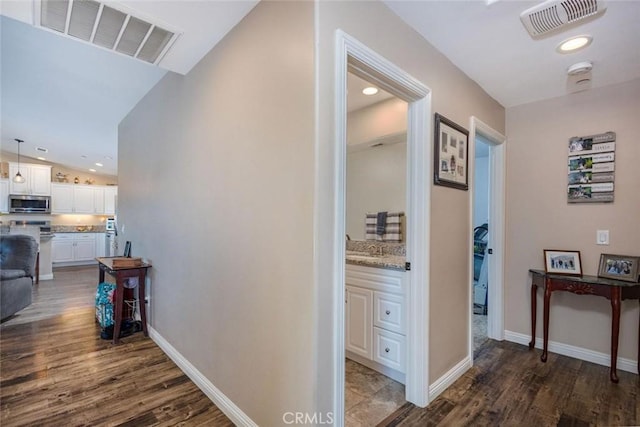 corridor with dark wood finished floors, visible vents, and baseboards