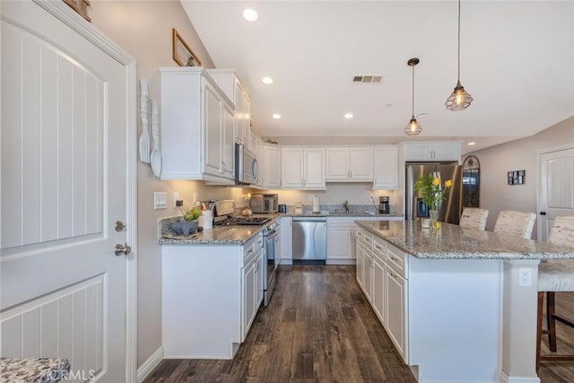 kitchen featuring appliances with stainless steel finishes, a breakfast bar area, visible vents, and white cabinets