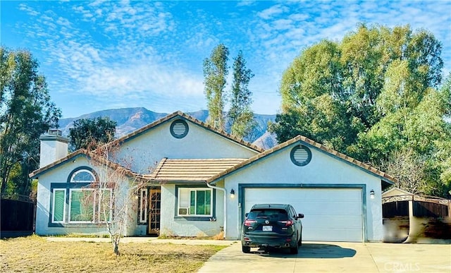 ranch-style house with an attached garage, driveway, a tiled roof, stucco siding, and a chimney