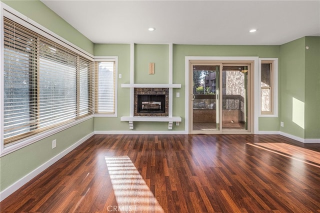 unfurnished living room with a wealth of natural light, a fireplace, baseboards, and wood finished floors