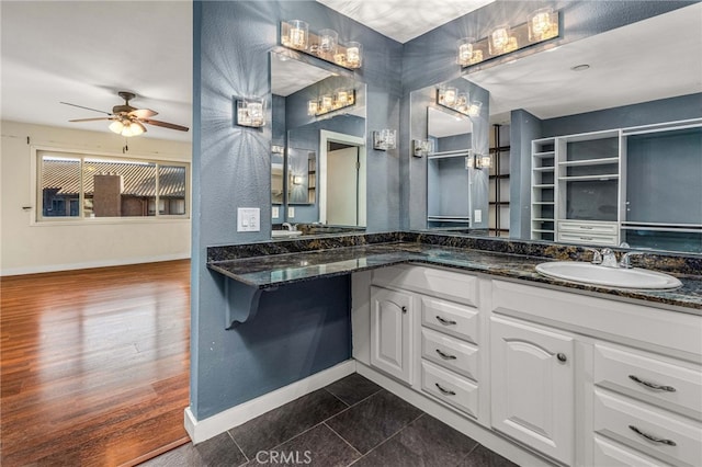 bathroom with ceiling fan, a sink, baseboards, and double vanity