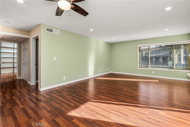 empty room with wood finished floors, visible vents, and baseboards