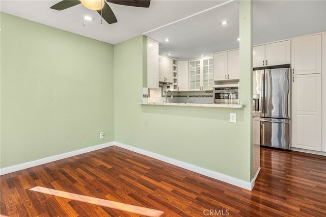 kitchen featuring stainless steel appliances, baseboards, white cabinets, and dark wood-type flooring