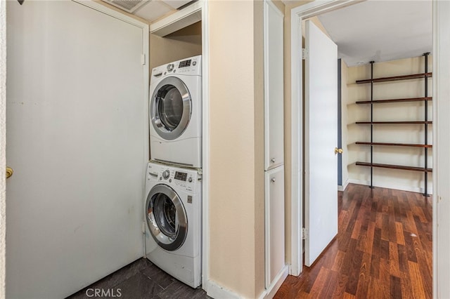 laundry area with dark wood-style floors, stacked washer / drying machine, and laundry area