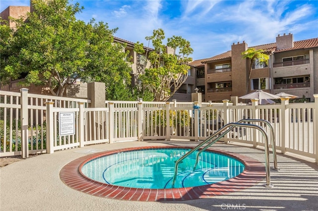 view of swimming pool with fence and a community hot tub