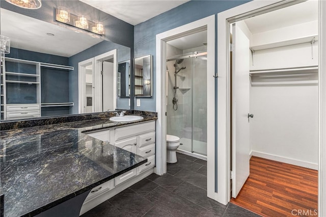 bathroom with baseboards, a shower stall, toilet, and vanity