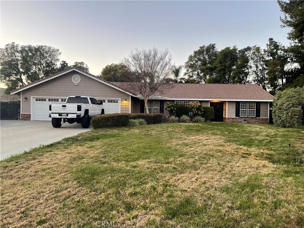 ranch-style house with driveway, an attached garage, and a front yard