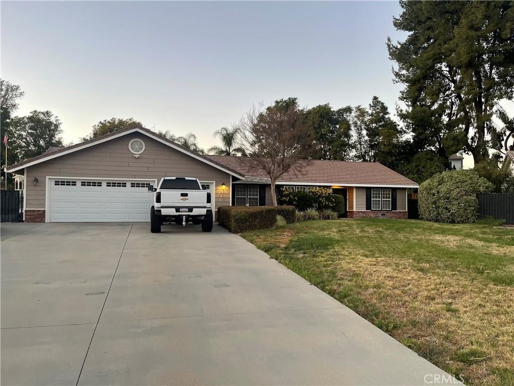 ranch-style house featuring a garage, concrete driveway, brick siding, and a front yard