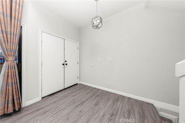 foyer with lofted ceiling, wood finished floors, baseboards, and a chandelier