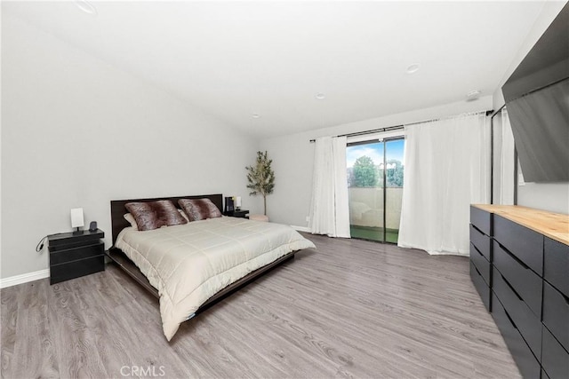 bedroom featuring access to outside, wood finished floors, and baseboards