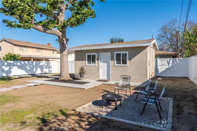 back of property with a patio area, a fenced backyard, a fire pit, and stucco siding