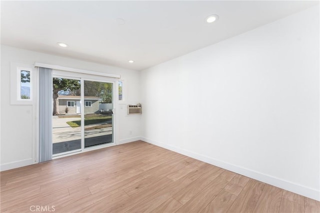 spare room featuring baseboards, recessed lighting, a wall mounted air conditioner, and light wood-style floors