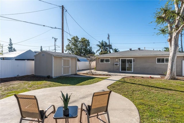 back of house featuring a fenced backyard, a storage unit, an outbuilding, and a patio