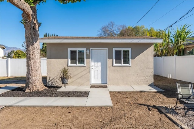 view of front facade featuring fence and stucco siding