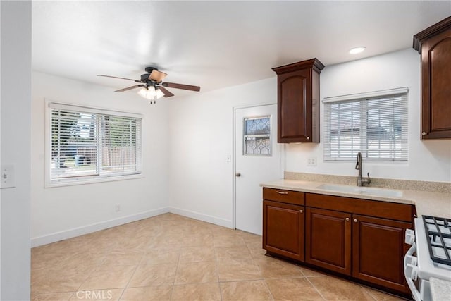 kitchen with a healthy amount of sunlight, light countertops, white range with gas cooktop, and a sink