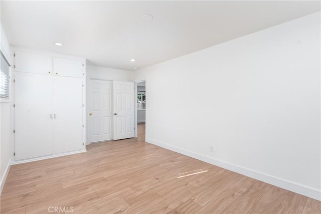 unfurnished bedroom with light wood-type flooring, a closet, baseboards, and recessed lighting