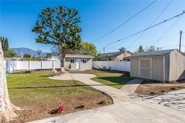 view of yard with an outbuilding, a patio area, a fenced backyard, and a mountain view