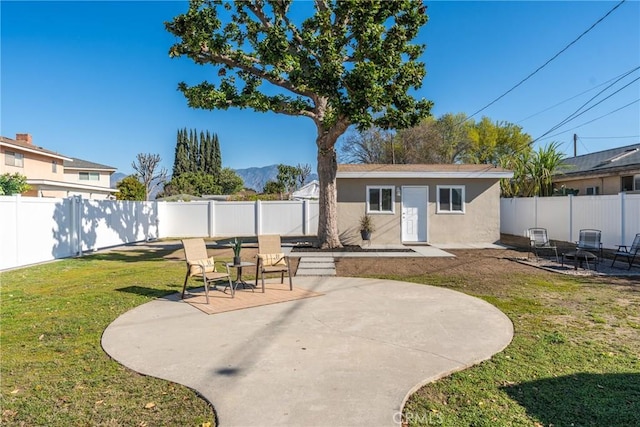 back of property featuring an outbuilding, a yard, a patio, stucco siding, and a fenced backyard