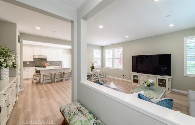 living room with baseboards, recessed lighting, and light wood-style floors