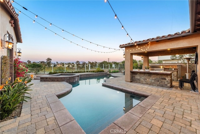 view of pool with exterior kitchen, a patio area, fence, and a pool with connected hot tub