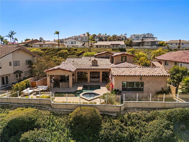 back of property with a tile roof, a fenced backyard, a residential view, and stucco siding