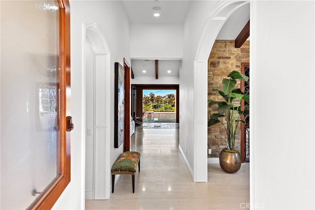 hall with arched walkways, beam ceiling, and recessed lighting