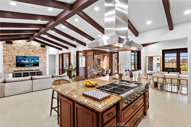 kitchen featuring island range hood, light stone counters, open floor plan, french doors, and a kitchen bar