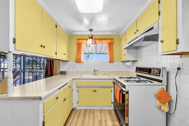 kitchen with a sink, light countertops, under cabinet range hood, and white range with gas cooktop