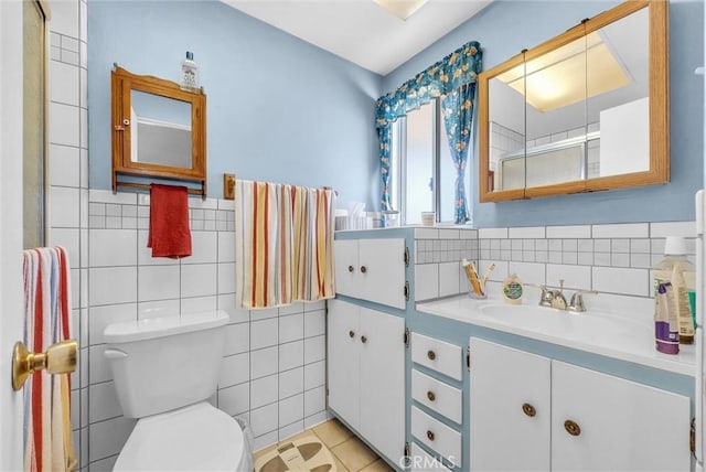 full bathroom featuring a shower with door, tile walls, toilet, vanity, and tile patterned floors