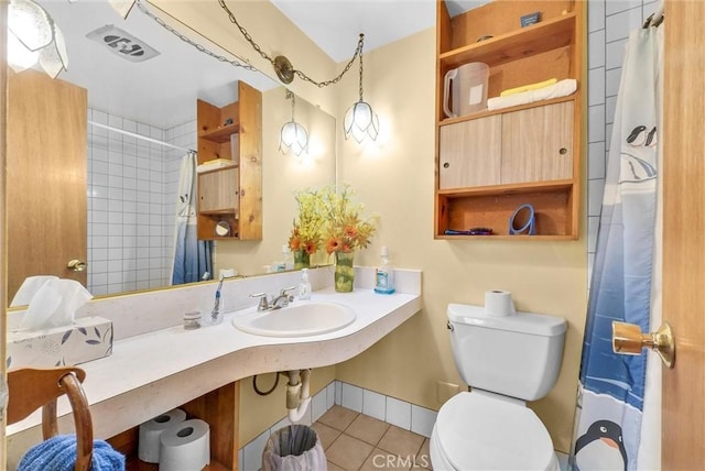 bathroom featuring baseboards, visible vents, toilet, tile patterned floors, and a sink