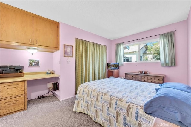 bedroom with light carpet and built in desk