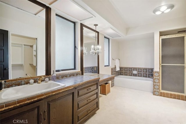 bathroom featuring a stall shower, a chandelier, a bath, and vanity