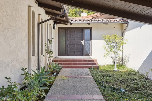 view of exterior entry featuring a tiled roof and stucco siding