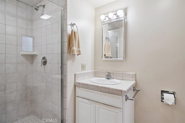 full bathroom with tiled shower and vanity