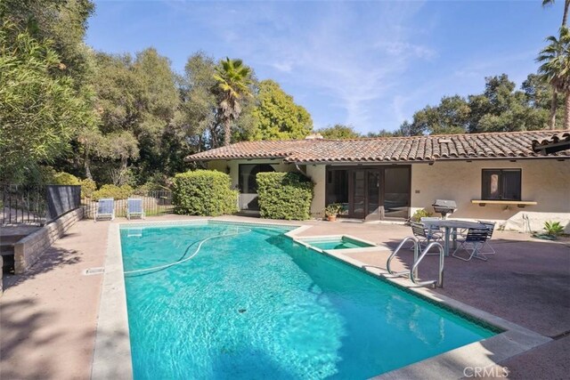 view of swimming pool featuring a fenced in pool, a patio area, fence, and an in ground hot tub