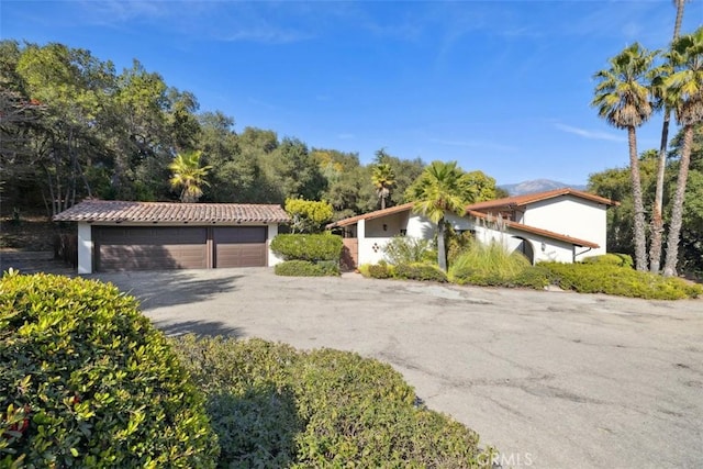 view of front of house with a tiled roof, a detached garage, and stucco siding