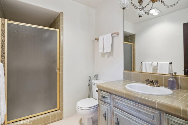 bathroom with a stall shower, vanity, toilet, and an inviting chandelier