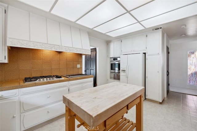 kitchen with visible vents, white cabinets, appliances with stainless steel finishes, a warming drawer, and tasteful backsplash