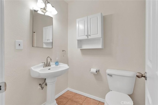 bathroom featuring toilet, baseboards, a sink, and tile patterned floors