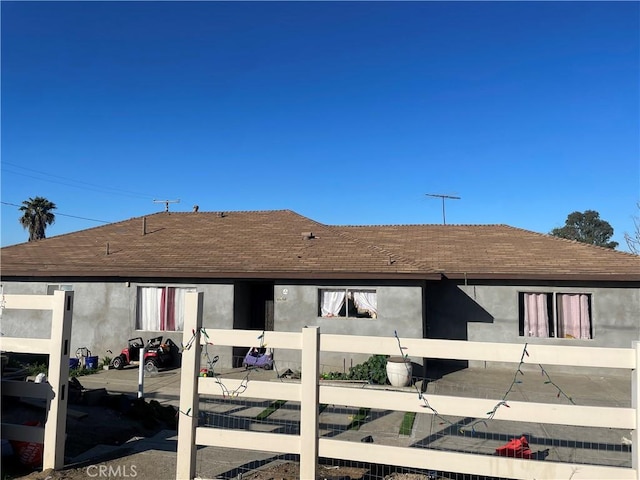 back of property with a shingled roof and stucco siding