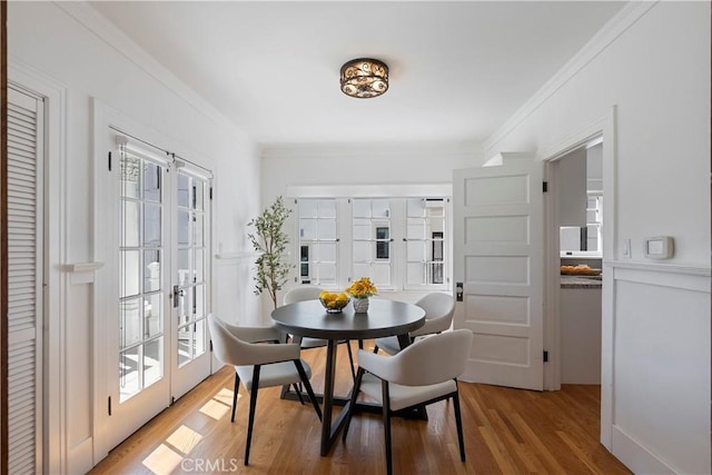 dining space featuring light wood-style flooring, crown molding, and french doors