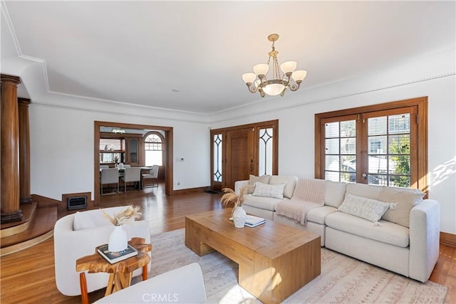 living area with a chandelier, baseboards, decorative columns, and light wood finished floors