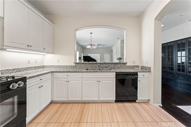 kitchen with arched walkways, white cabinetry, light stone countertops, a chandelier, and black appliances