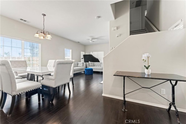 dining room featuring ceiling fan with notable chandelier, visible vents, wood finished floors, baseboards, and stairs