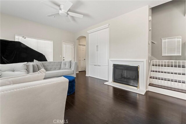1339 Castledale St, Riverside, CA 92501 - living area with a fireplace with raised hearth, arched walkways, a ceiling fan, and dark wood-style floors
