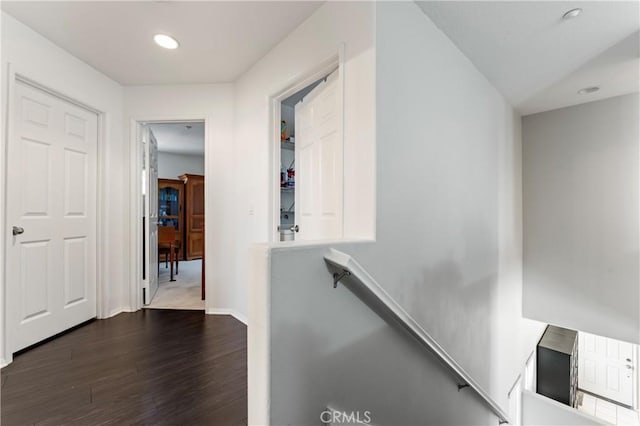 hallway with baseboards, dark wood finished floors, and an upstairs landing