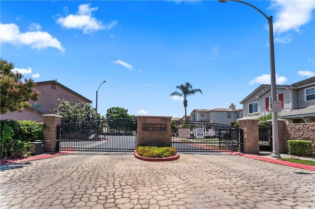 view of street featuring street lighting, a gate, a gated entry, a residential view, and curbs