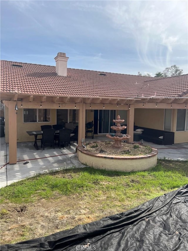 rear view of property with a chimney, a patio, a tiled roof, and stucco siding