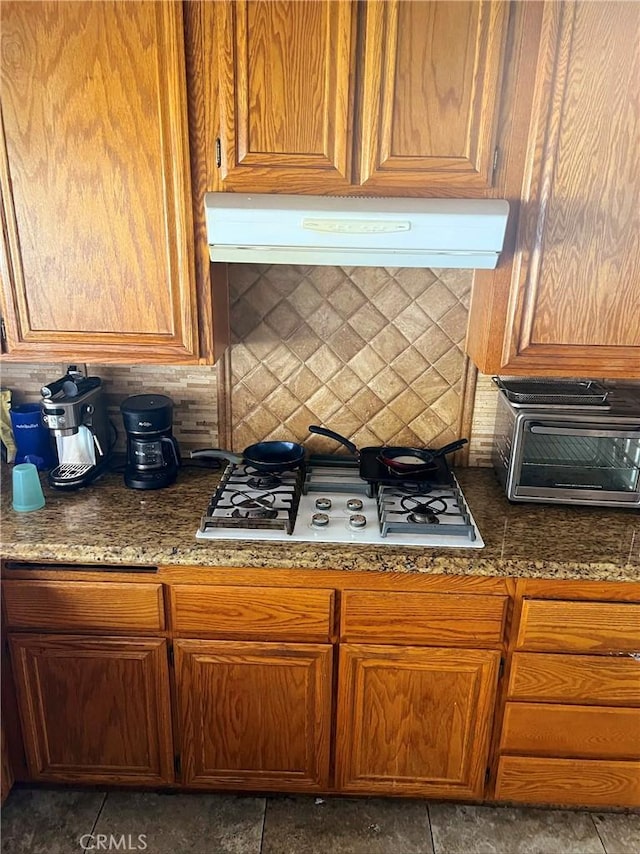 kitchen with backsplash, white gas cooktop, exhaust hood, and brown cabinets